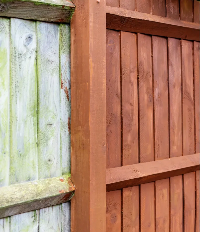 Side-by-side view of an old, weathered fence and a newly painted brown wooden fence.