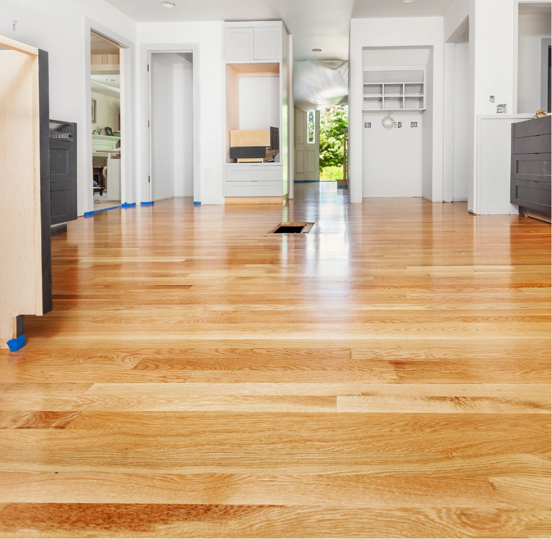 refinishing-2 Bright modern room with newly installed hardwood floors and white walls, under renovation.