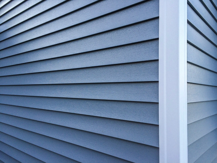 siding-1 Close-up of blue vinyl siding on the corner of a house with white trim.
